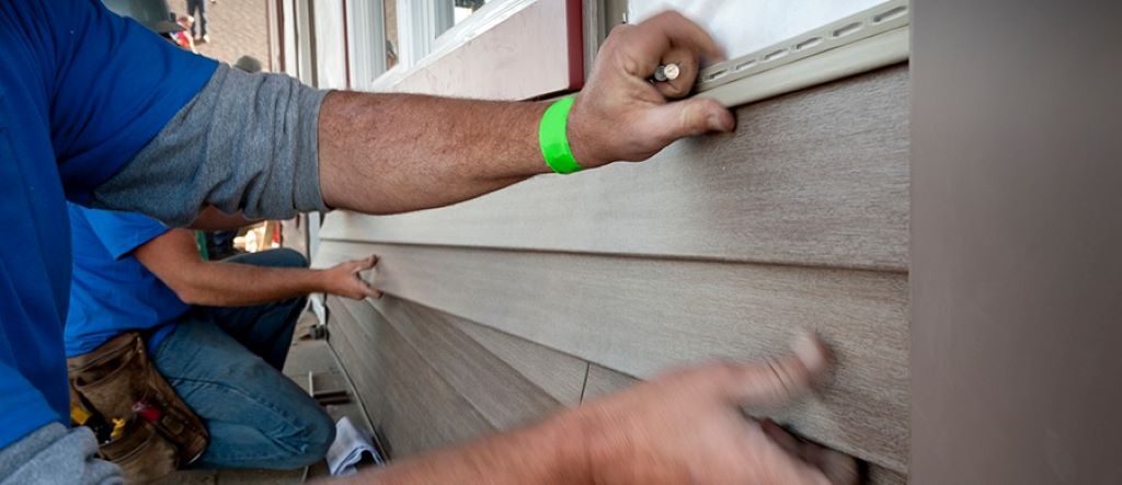 Worker removing vinyl-backed panels from a garage door for sustainable recycling