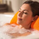 A cozy non-slip bath pillow attached to a white bathtub, cradling a relaxer's neck during a steamy soak.