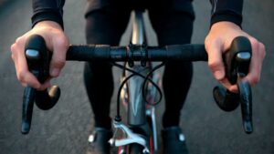 1. Cyclist adjusting handlebar grip position to prevent hand numbness during long ride