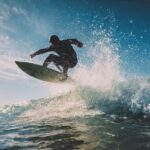 Surfer performing chop hop maneuver on wave with board lifting off water surface during choppy conditions