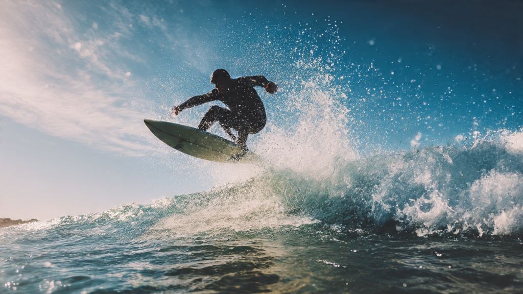 Surfer performing chop hop maneuver on wave with board lifting off water surface during choppy conditions