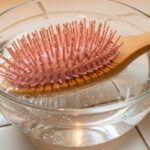 Clean hair brush being soaked in rubbing alcohol solution for lice sterilization treatment