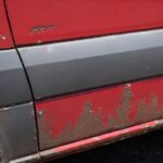 Close-up of rust damage on Sprinter van rocker panel showing surface corrosion and paint bubbling