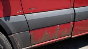 Close-up of rust damage on Sprinter van rocker panel showing surface corrosion and paint bubbling