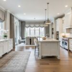 Modern open concept kitchen with white cabinets, wood flooring, and soundproofing features including area rug and fabric window treatments
