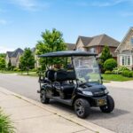 A modern street-legal golf cart parked on a sunny suburban neighborhood street.