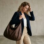 A woman holding an overstuffed, sagging hobo shoulder bag with a frustrated expression.