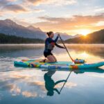 Person paddling a FunWater inflatable SUP board on a calm lake at sunrise.
